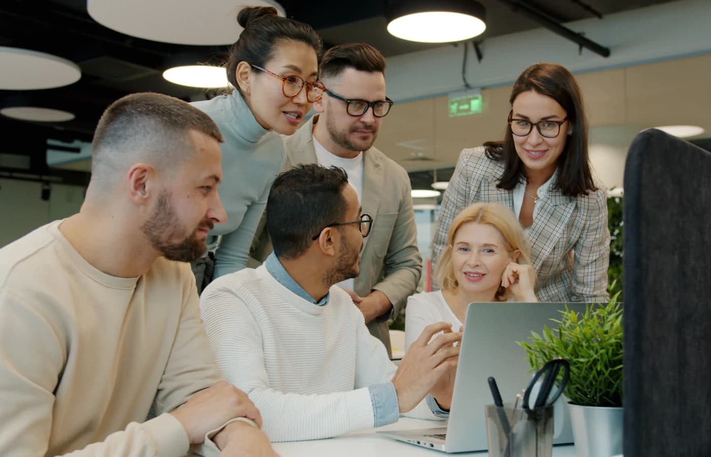 Team bespricht sich gemeinsam an einem Laptop im Büro