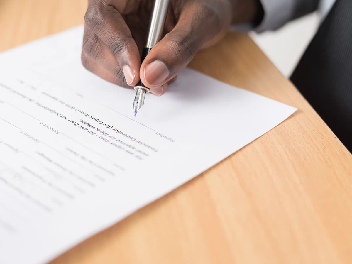 Hand mit Füller unterschreibt ein Vertragsdokument